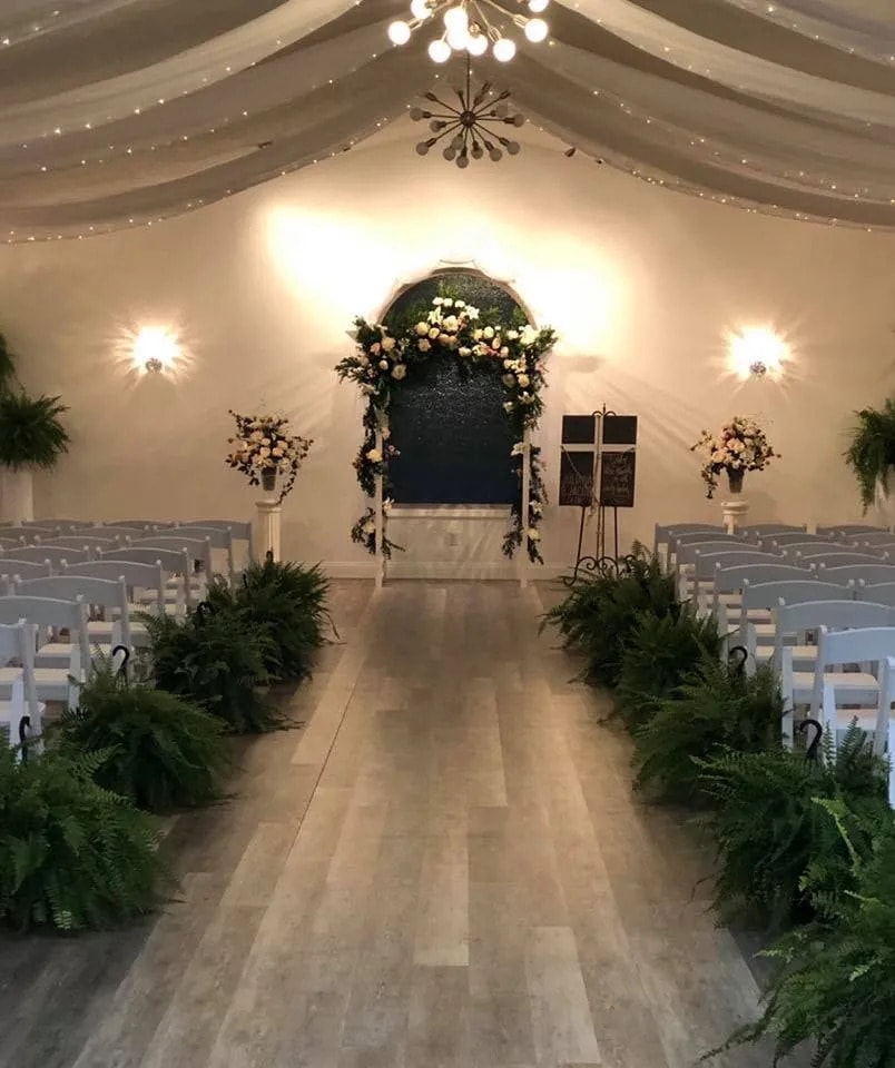 Indoor ceremony with floral arch and ferns